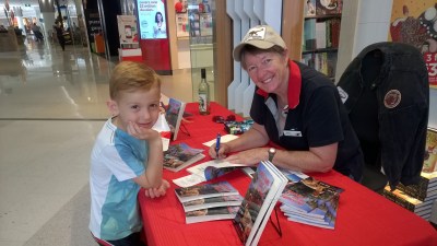 Rose Siva signing a book for a young reader